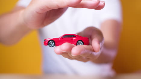 camión de juguete en la mano del concepto de mujer para seguros, compra, alquiler, combustible o costos de servicio y reparación