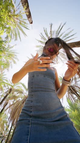 young woman with flying hair under palm trees on a sunny day