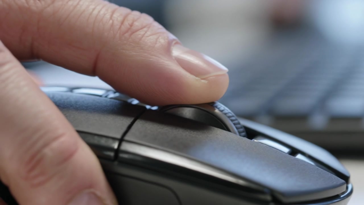 Applying fingertip pressure, right hand rotating scroll wheel on desk, scrolling document