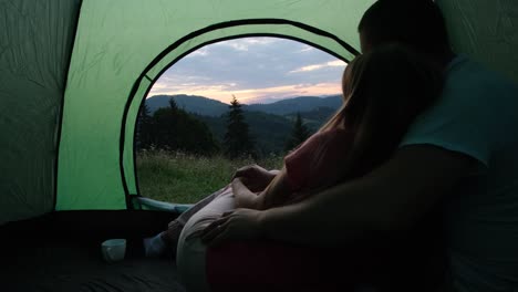 loving couple admiring flowers together in a tent loving couple admiring flowers together in a tent loving man gave daisies while sitting in a tent while camping young hikers resting in the mountains