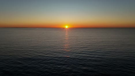 sun sets on horizon next to ocean ship near perth, western australia