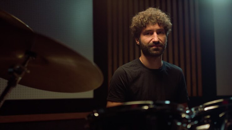 Artista gioioso che riposa in sala. Batterista sorridente che guarda la telecamera in studio.