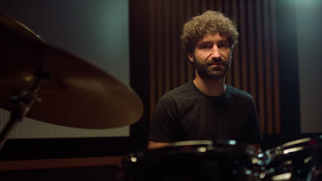 joyful artist resting in hall. smiling drummer looking to camera in studio.