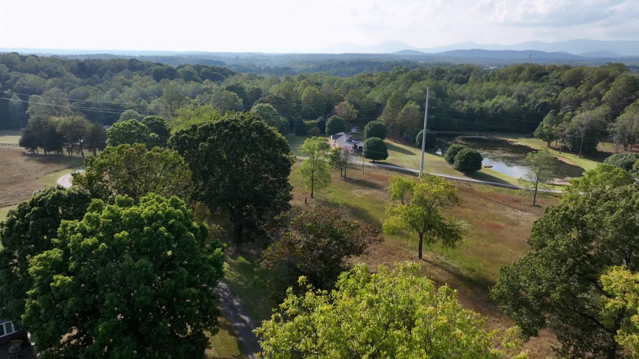 Drone flyover American countryside with farmers houses and parking cars. Sunset time in Green scenic district of Virginia, USA. Wide shot. Peaceful scene