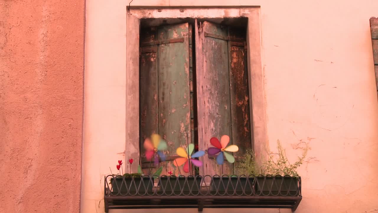 los molinetes giran en una sembradora fuera de una ventana antigua en venecia italia