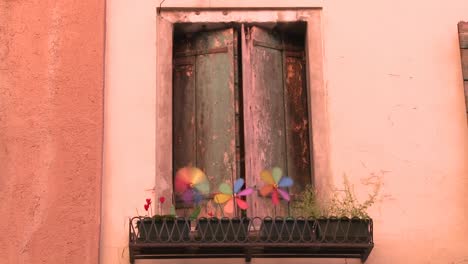 pinwheels spin in a planter outside an old window in venice italy