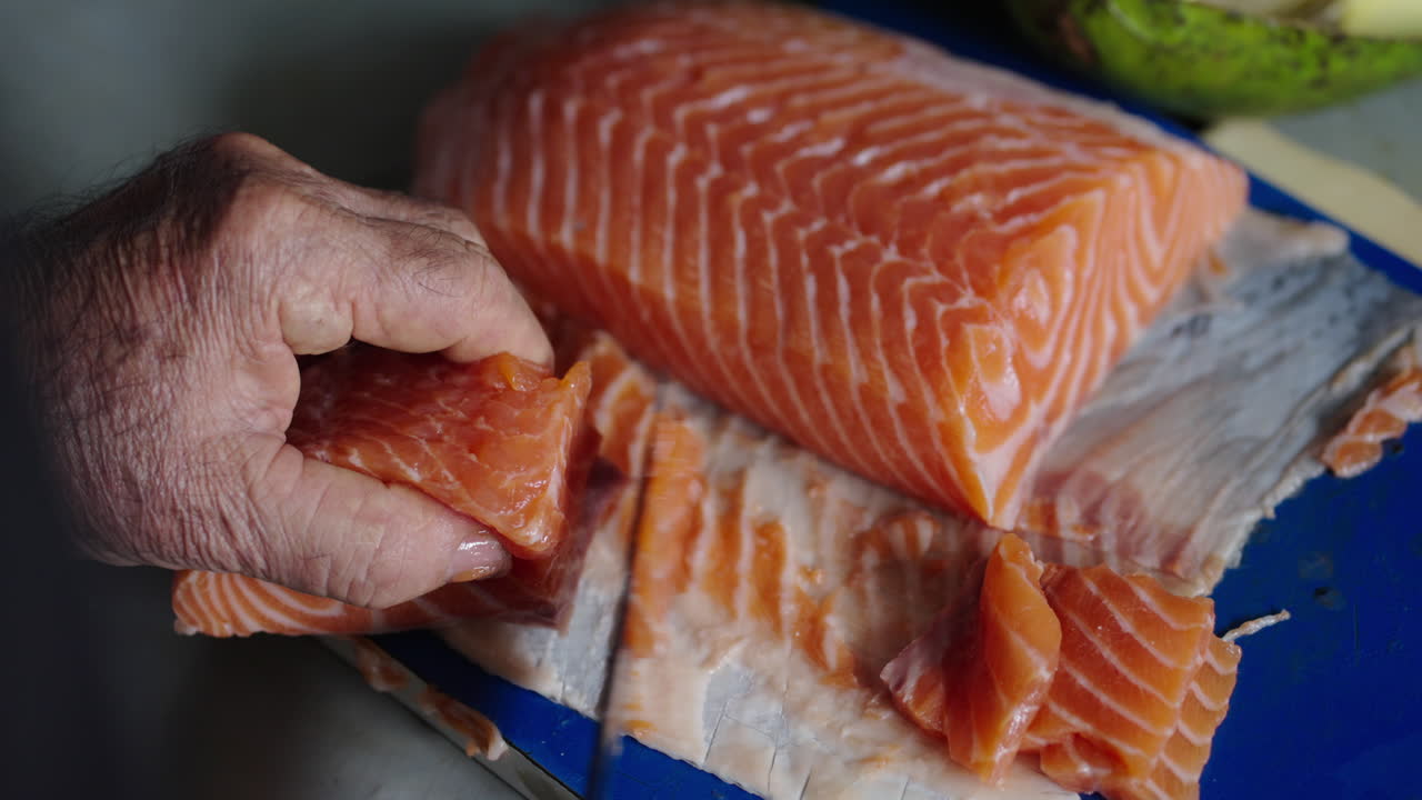 Close-up view of raw salmon fillet cut by chef for traditional Japanese cuisine