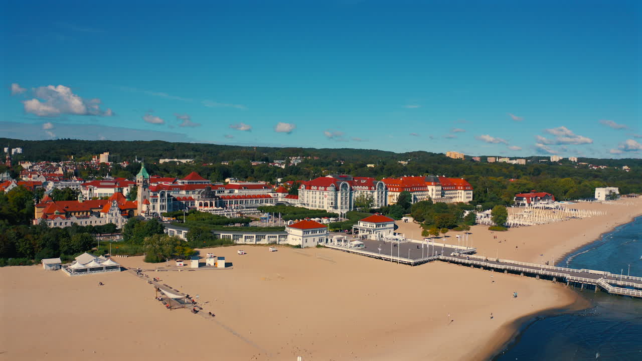 Aerial view of drone flying towards the city of Sopot, Poland with baltic sea and pier in the foreground at the sunny summer day