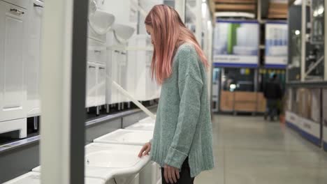 Mujer-Rubia-Está-Eligiendo-Un-Nuevo-Fregadero-De-Cerámica-En-Una-Tienda