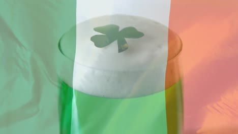 trébol cayendo en una cerveza verde contra un fondo de bandera irlandesa para el día de san patricio