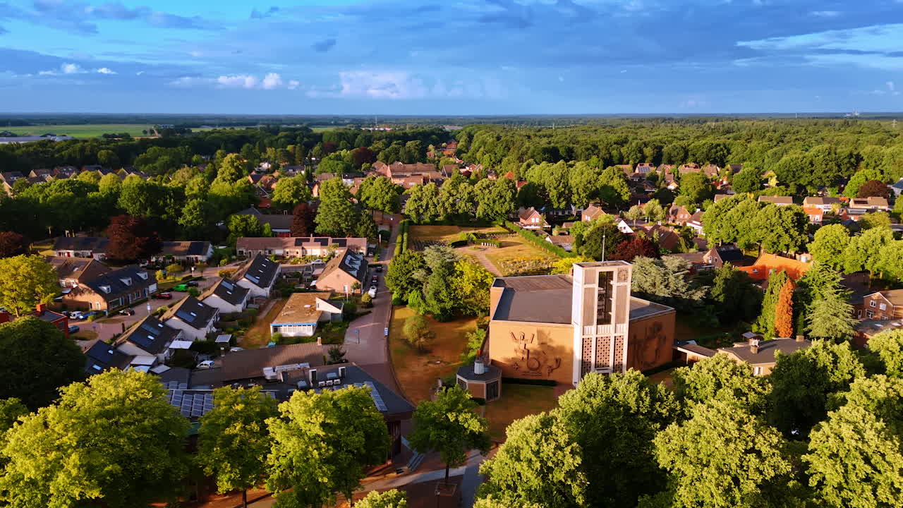 Unusually shaped building of H.Theobalduskerk Church in the center of the town. Drone flight over the sunny scenery of Overloon, Netherlands