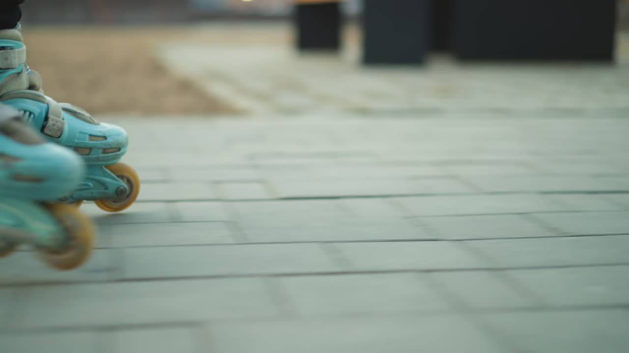 A close-up shot capturing a rollerblade in motion as it glides across a paved path in a park. The focus is on the rollerblade's wheels and the smooth movement over the pavement