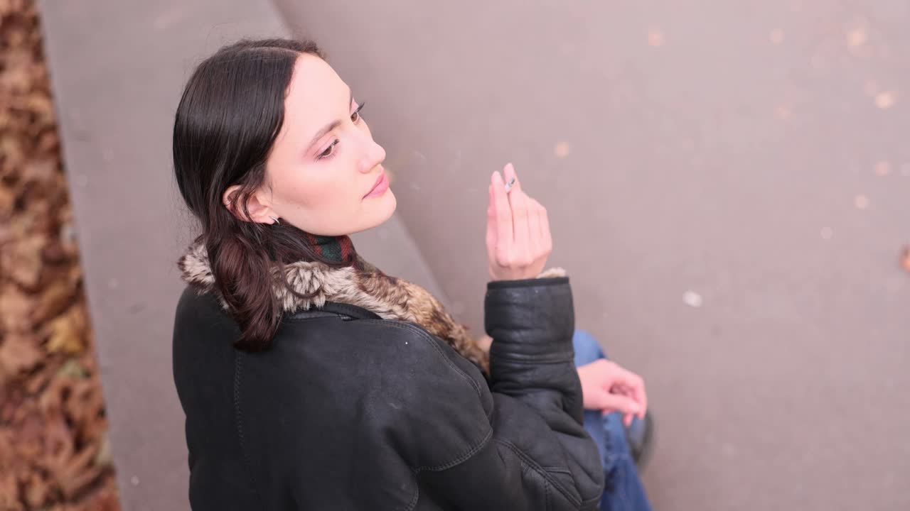 Una donna fuma una sigaretta godendosi la calma atmosfera di una giornata autunnale.