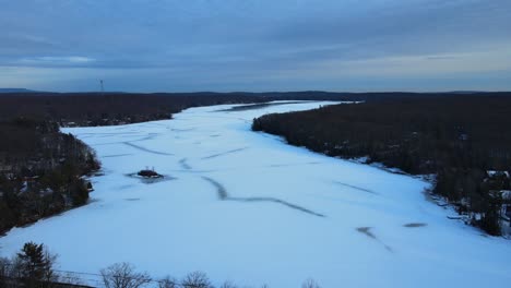 drone footage of a frozen, snowy lake during winter with overcast skies