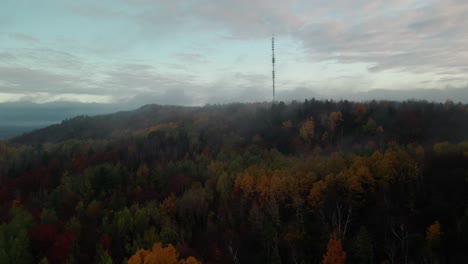 Torre-De-Comunicaciones-En-La-Cima-De-Una-Colina-Rodeada-Por-Los-árboles-Otoñales-En-El-Bosque-En-Una-Mañana-Nublada-En-Quebec,-Canadá