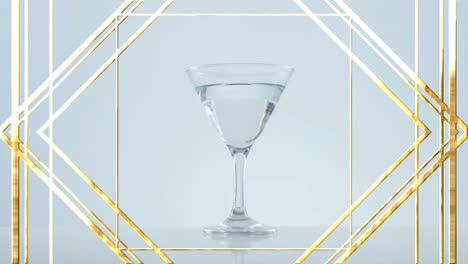 golden frame design pattern over olives falling into cocktail glass against grey background