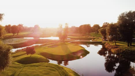 A-rising-Aerial-establishing-drone-shot-shows-a-golf-course-with-ponds-during-sunset-in-Warsaw,-Poland