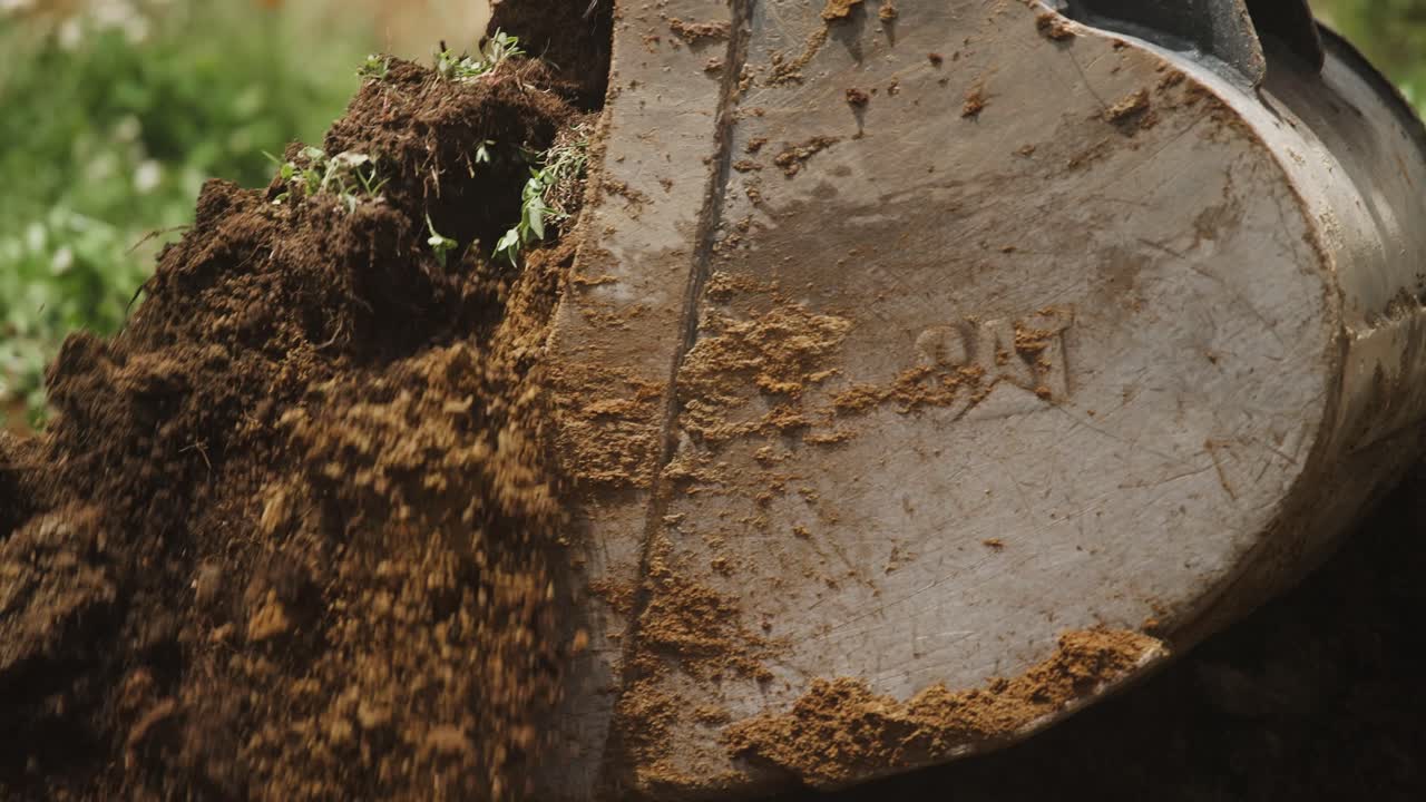 Dettaglio al rallentatore di un escavatore che scava terra ed erba fresca
