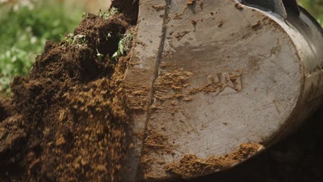 detalle excavadora a cámara lenta cavando a través de la tierra y la hierba fresca