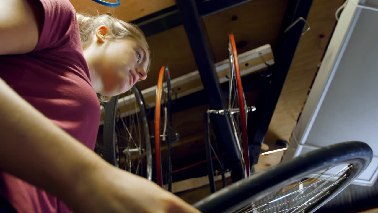 Woman checking bicycle tyre at workshop 4k