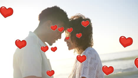 animation of hearts moving over diverse couple in love touching heads on beach in summer