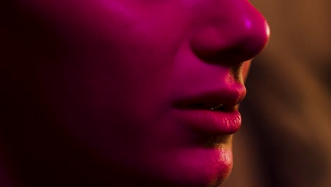 woman flinches and reacts close up on mouth lit by multiple colours