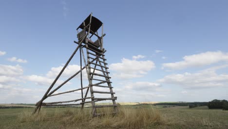 Lapso-De-Tiempo-De-Las-Nubes-Moviéndose-A-Través-Del-Cielo-Azul-Detrás-De-La-Torre-De-Vigilancia-De-Madera-En-El-Campo