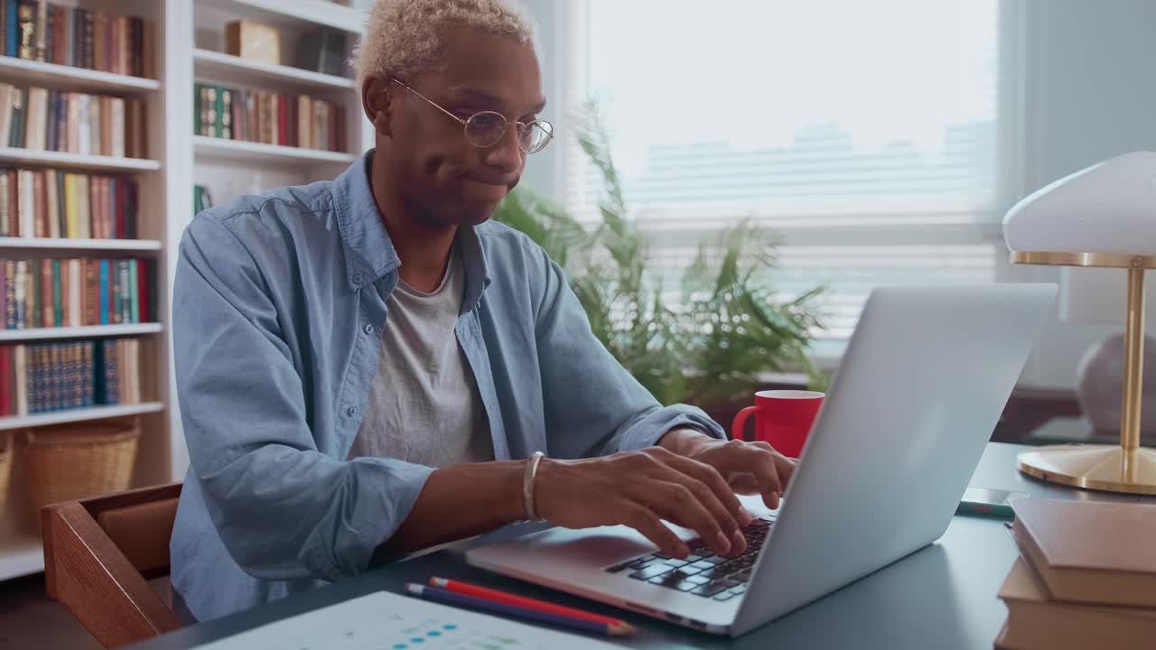 Serious afro american millennial man working on laptop in office