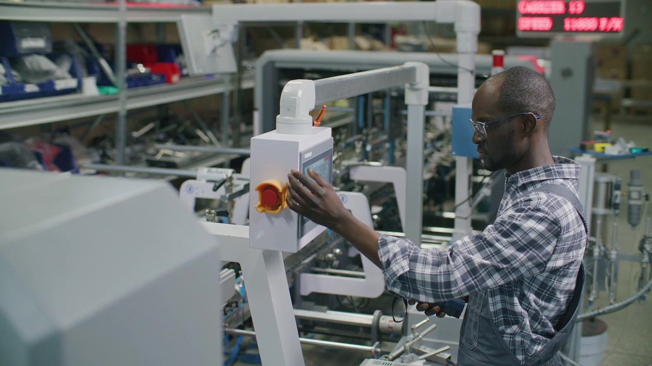 Black Worker Operating Automated Machine Console in Printing Factory