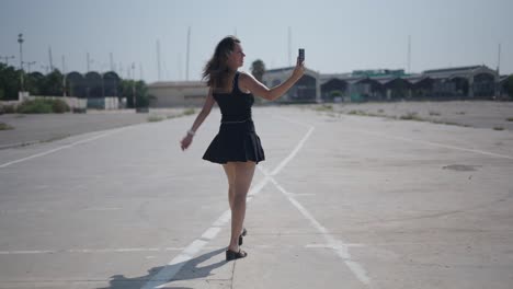 woman taking selfie while walking in an empty parking lot
