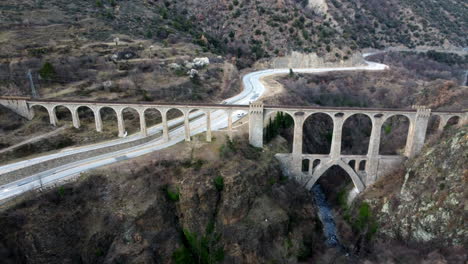 Wide-aerial-landscape-view-of-the-Pont-Séjourné-in-Fontpédrouse,-France,-crossing-a-highway