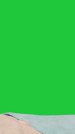 Vertical-Video-Summer-Holiday-Concept-Of-Sunglasses-Sun-Hat-Camera-Beach-Towel-On-Sand-Against-Green-Screen-1