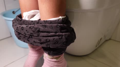 child sitting on toilet, removing pants