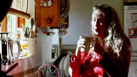 Mature-woman-having-coffee-in-kitchen-at-home-4k