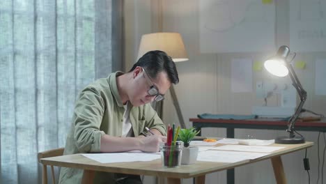 아시아인 디자이너가 사무실에서 레이아웃을 그리는 동안 생각하고 있습니다.