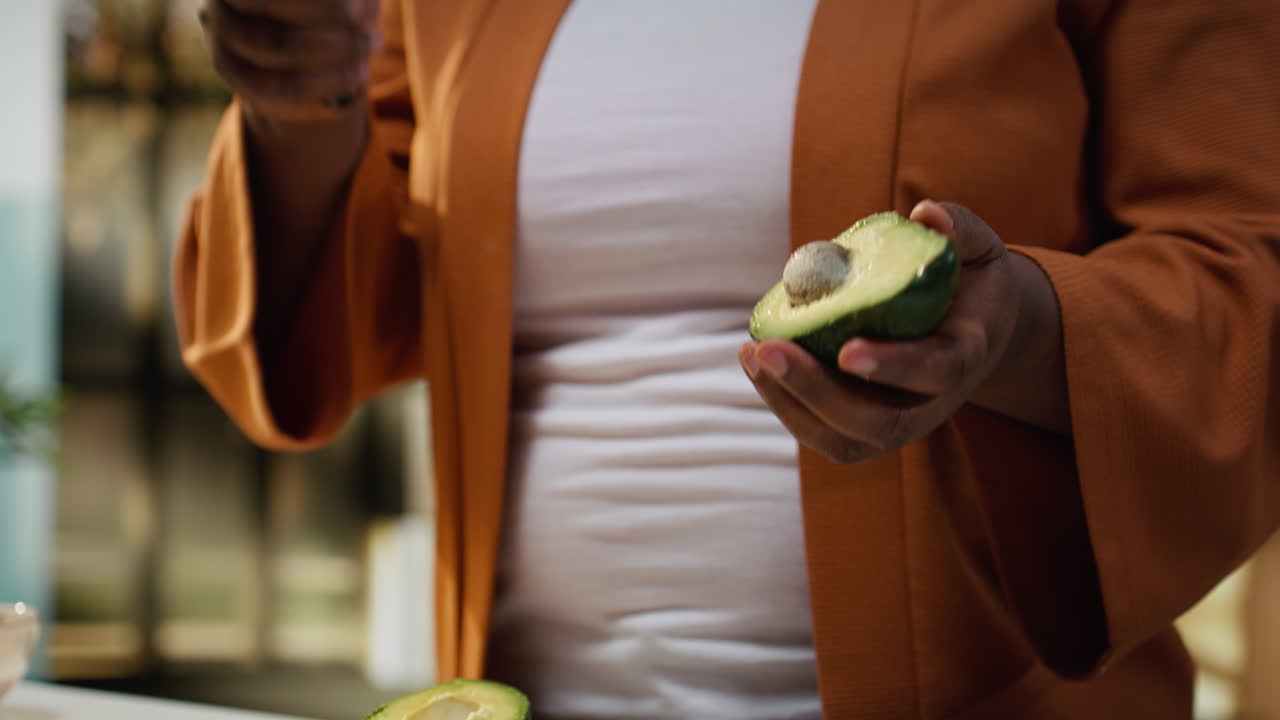 Donna afroamericana registra mentre taglia un avocado in un vlog di cucina sul bancone della cucina
