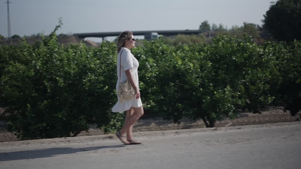 道路脇の道を歩く女性