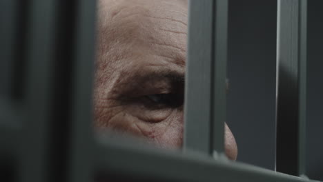 Close-Up-of-Prisoner-in-Orange-Uniform-Holding-Metal-Bars-in-Prison-Cell----------(Stock-Footage)