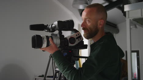 mannelijke filmcameraoperator die de lens richt op een op een statief gemonteerde camera die film of video opneemt in studio 1