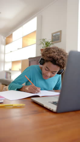 vertical video of biracial boy using laptop for online class, slow motion