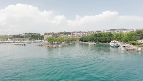 Drone-flying-towards-entrance-of-small-yacht-harbor-on-a-sunny-summer-day