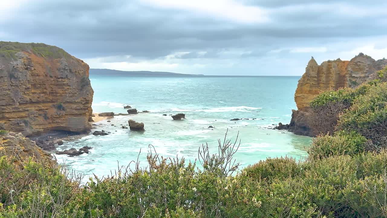 A serene coastal landscape with cliffs and ocean waves under cloudy skies, captured at Great Ocean Road, Australia