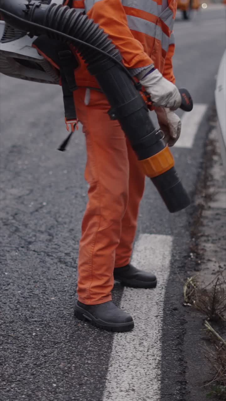 Worker using a leaf blower on a road