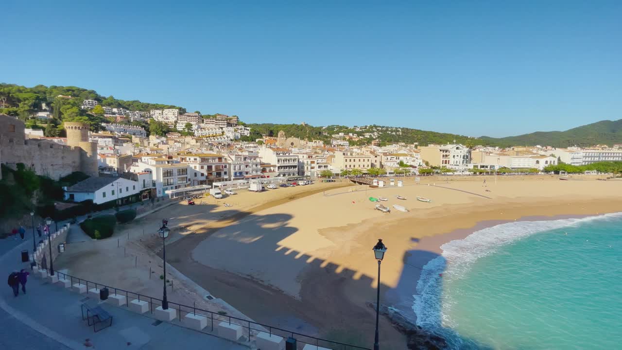 Baia di Tossa de Mar vista dal castello alla spiaggia con sabbia grossolana e acqua di mare blu turchese, antico borgo medievale di pescatori fortificato sul Mar Mediterraneo