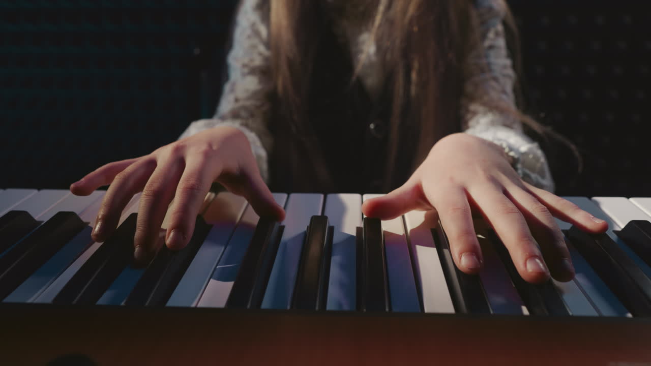 estudiante toca el piano en la academia de música. niña pequeña aprende sonidos producidos por las teclas de un instrumento musical en un estudio de audio. arte en la música