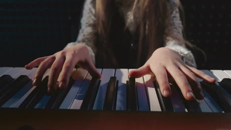 student performs on piano in music academy. petite girl learns sounds produced by keys of musical instrument in audio studio. artistry in music