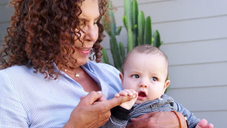 grandmother sitting outside house playing with baby grandson