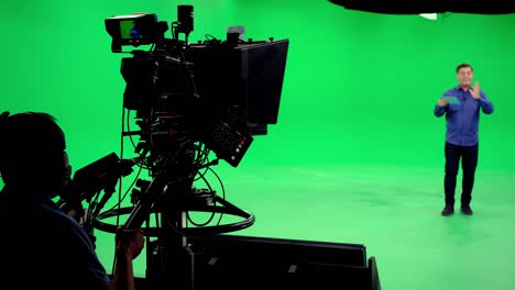 the cameraman follows the announcer in a professional green screen studio. the professional looks all the shooting equipment; lights, camera, green screen