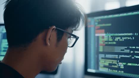 Asian programmer writing source code in a dark office, focusing on complex algorithms and software development tasks