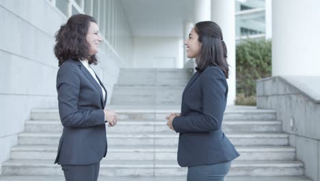 felices y amistosos colegas de oficina en trajes reuniéndose afuera.